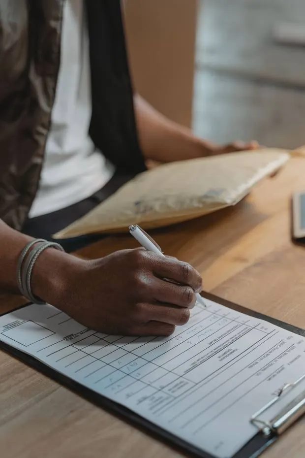 Hand signing a delivery requisition form on a clipboard